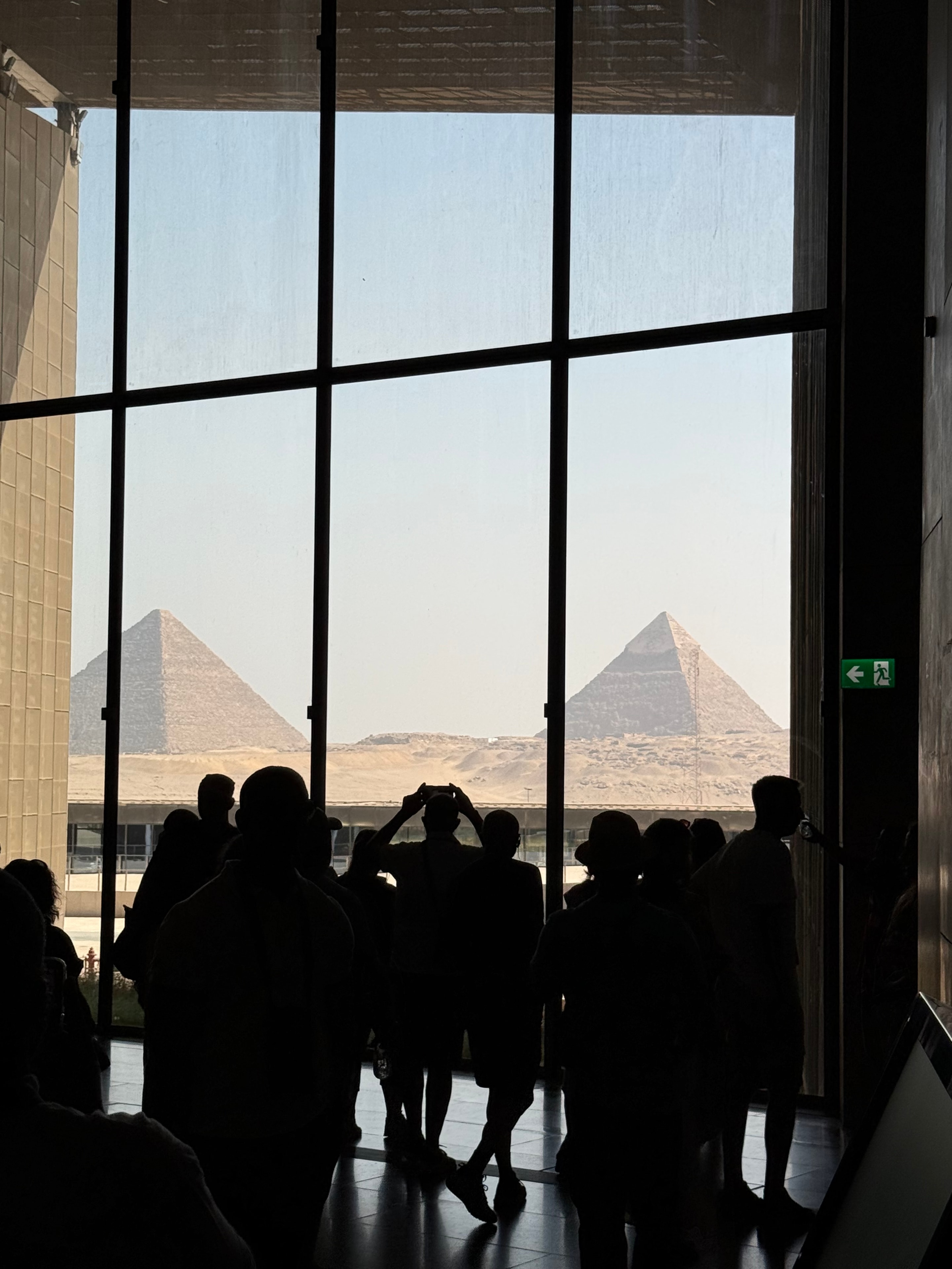 Grand Egyptian Museum — visitors looking through monumental windows toward the Giza Pyramids, world-class cultural heritage and discovery